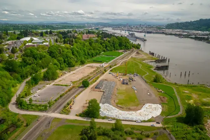field near a river with construction site