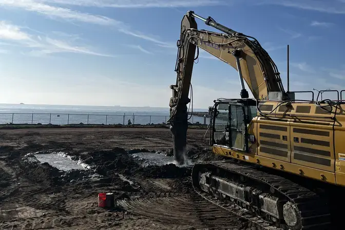excavator with attachment performing soil mixing on beach front property