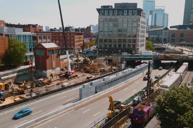construction site bordered by a highway and rail tracks