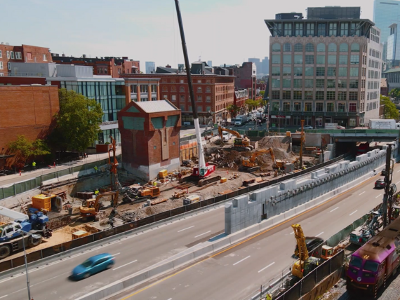 construction site bordered by a highway and rail tracks