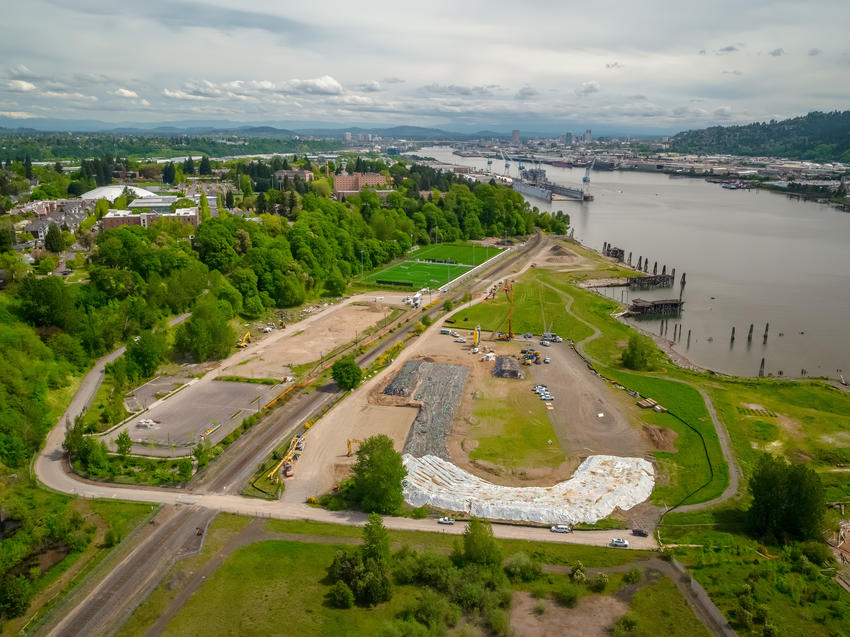 field near a river with construction site